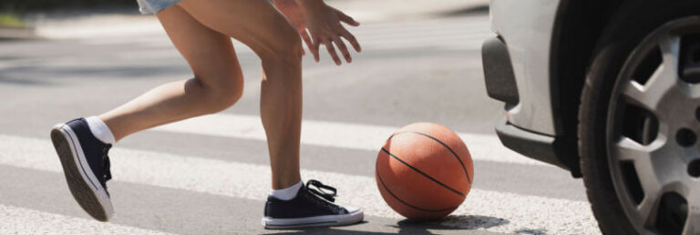person running into road with cars chasing a ball