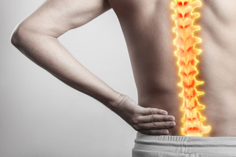 man holding his lower back due to spinal cord pain