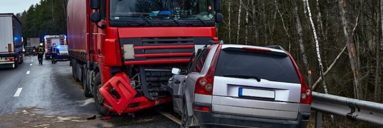 Scene of truck accident with red truck and white car parked on roadside.