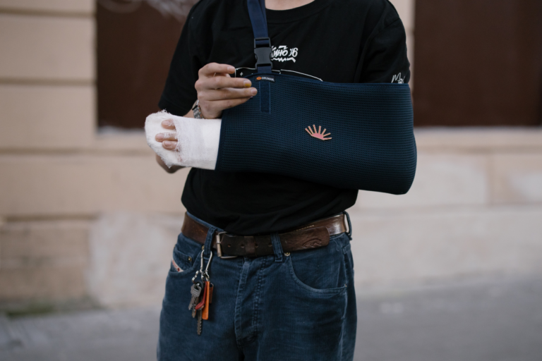 a person wearing a long sleeve navy shirt with an arm in a sling